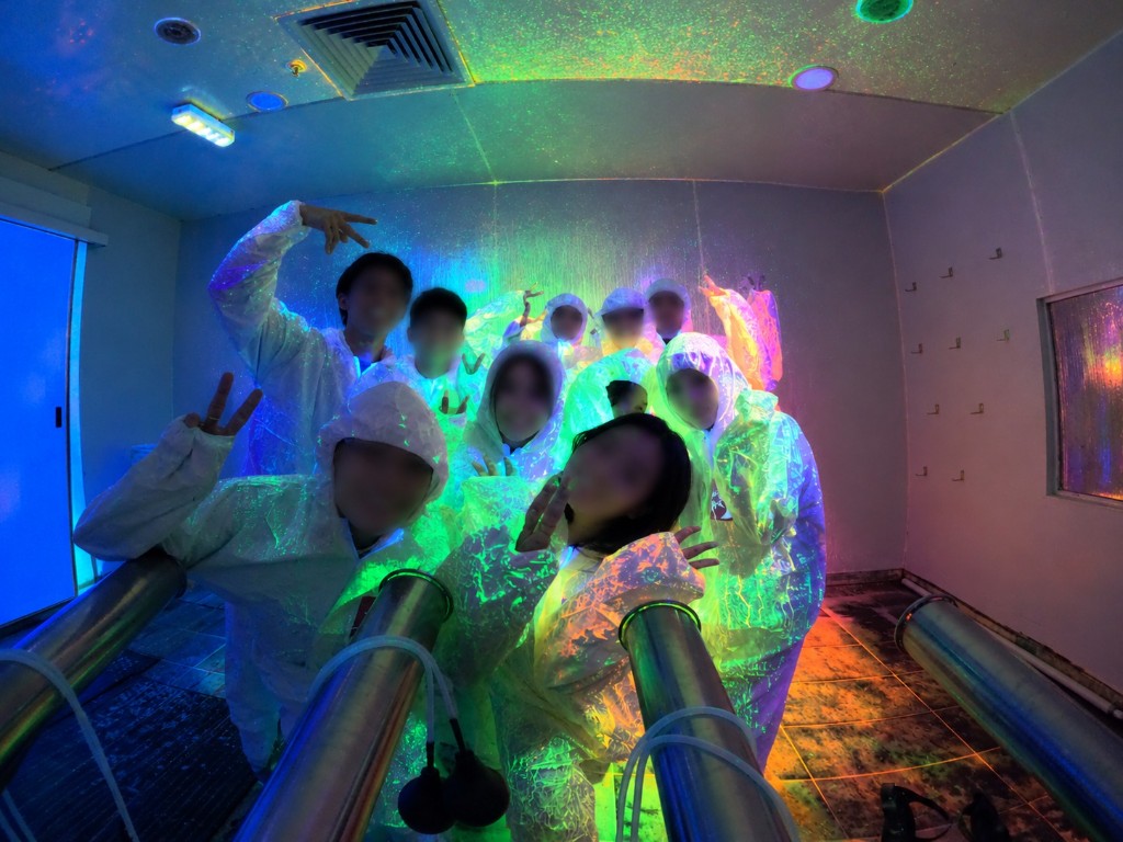 The team in white coveralls at a group activity, faces blurred